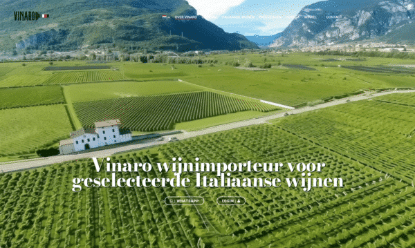 Aerial view of a lush vineyard with a white winery building and distant mountains, overlaid by large Dutch text promoting Vinaro as importer of selected Italian wines.